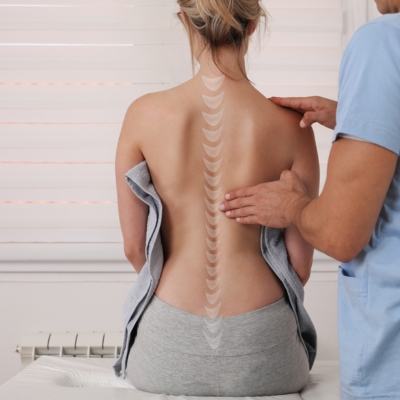 The chiropractor performs a spinal assessment on a female patient to diagnose and fix poor posture.
