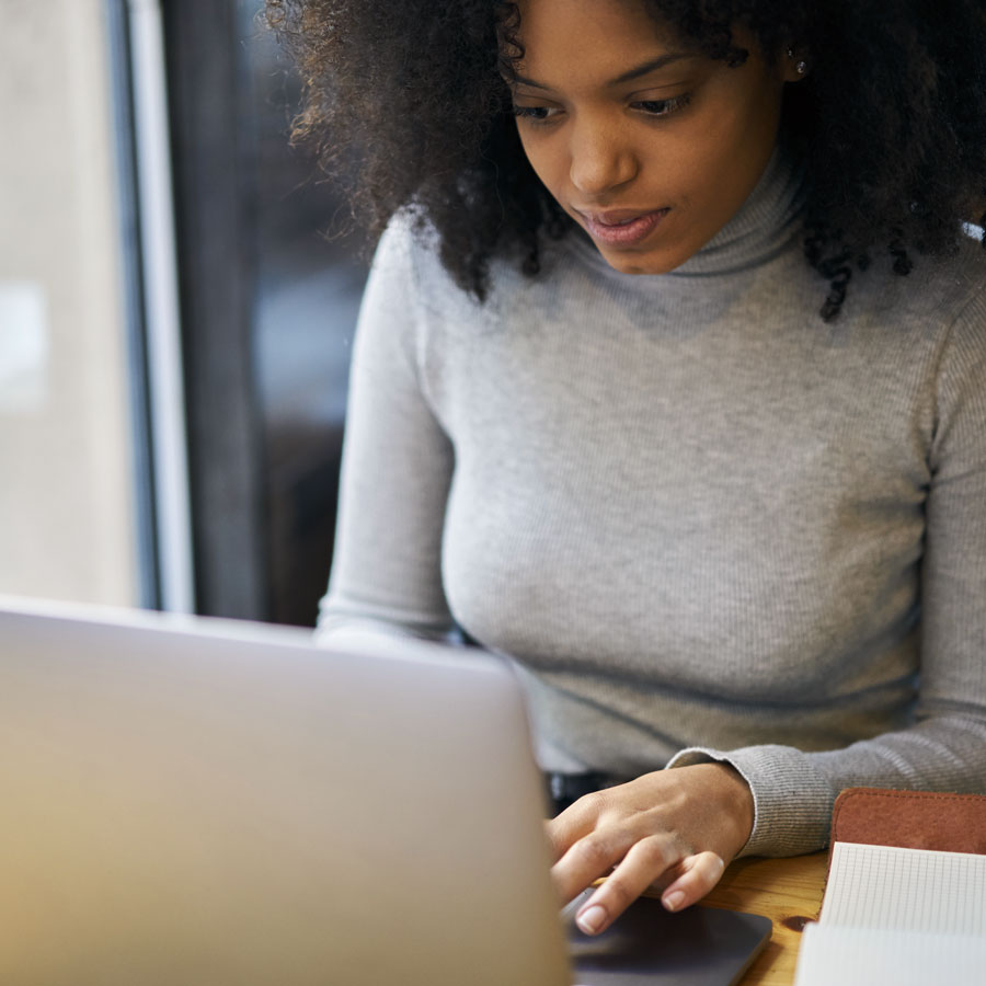 schedule-chiropractic-appointment-axis-charleston Woman using a laptop to schedule a chiropractic appointment at Axis Chiropractic in Charleston, SC.