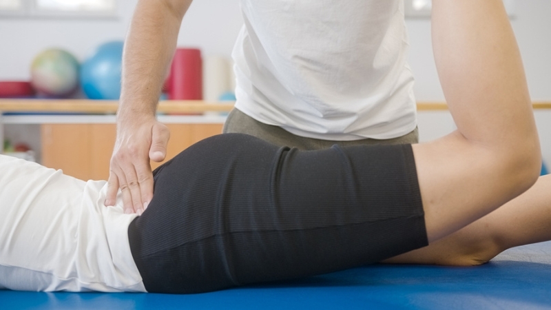 The chiropractor is performing a lower back adjustment to relieve sciatica pain.